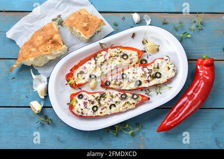 Mediterranean cuisine - Baked red pointed peppers filled with Greek feta and goat cream cheese, onions, leek, herbs and black olives Stock Photo