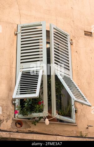 Menton, France - July 2, 2020: An old window with half-open shutter in old town of Menton Stock Photo
