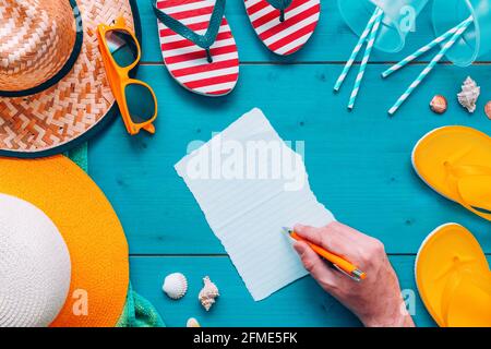 Man writing note on a piece of paper on the beach, top view flat lay Stock Photo