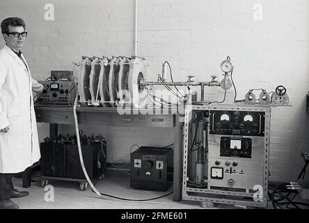 1963, historical, a white-coated male technician standing beside equipment being tested by an oscilloscope, often known simply as a scope or o-scope, a type of electronic test instrument that graphically displays signal voltages and measures voltage waves. Stock Photo