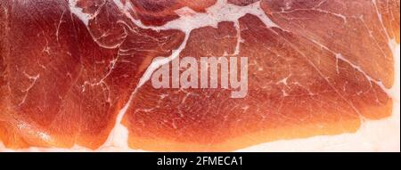 Jamon or dry-cured ham produced in Spain texture close up. Food background. Stock Photo