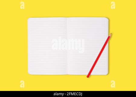 School or office notebook with red pencil isolaed on yellow background. Top view. Mock up Stock Photo