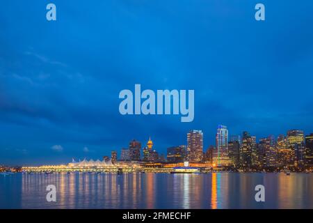 Vancouver, BC, Canada - July 1 2014: Urban illuminated cityscape skyline of downtown Vancouver, B.C. and Coal Harbour from Stanley park seawall at nig Stock Photo