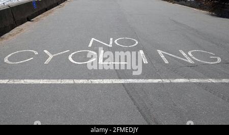 Sign written on the road next to the beach saying 'no cycling' in capital letters Stock Photo