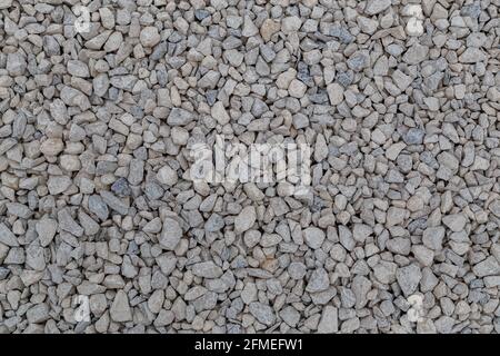 Dry white limestone ballast flat full frame background. Small gray dusty broken macadam stones texture. Viiew from above. Stock Photo