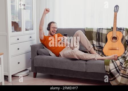 Handsome man playing on the guitar on the couch at home Stock Photo
