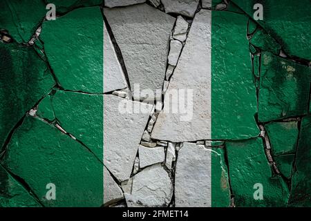 National flag of Nigeria depicting in paint colors on an old stone wall. Flag  banner on broken  wall background. Stock Photo