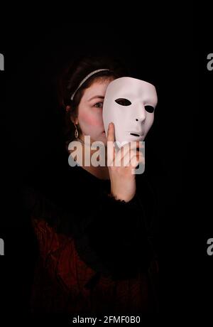 Woman in costume holding mask to her face Stock Photo