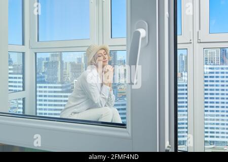 View through the window of a woman who sits on the balcony of her new apartment Stock Photo