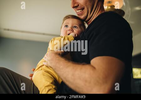 Cropped shot of a cute boy with his father at home. Man sitting with his baby at home. Stock Photo