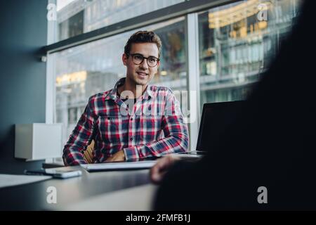 Young businessman sitting in a meeting. business professional listening to the discussion in meeting. Stock Photo