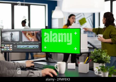 Video maker editing movie using post production software working in creative agency at pc with green screen, chroma key, mock up isolated display. Videographer processing audio film montage Stock Photo