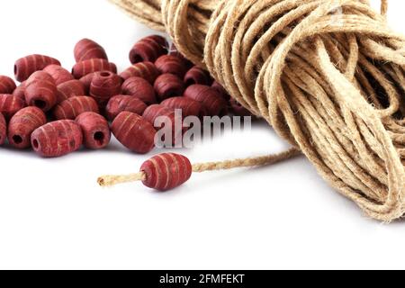 Wooden beads with natural jute string Twine Rope on white background. Close up, macro. Stock Photo