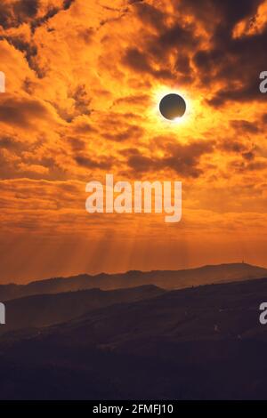Amazing scientific natural phenomenon. The Moon covering the Sun. Total solar eclipse with diamond ring effect glowing on sky above mountain range. Se Stock Photo