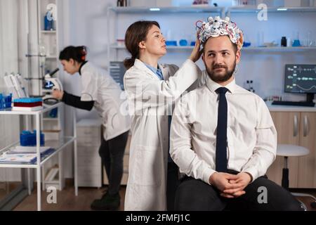 Neurologist doctor analysing brain of man and nervous system using brainwave scanning headset. Researcher using high tech developing neurological innovation monitoring side effects on monitor screen Stock Photo
