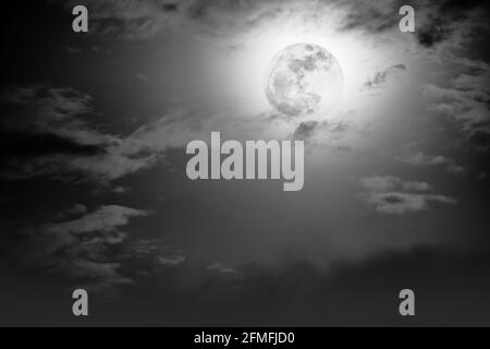 Background of nighttime sky with cloud and full moon with shiny. Natural beauty at night with moon behind cloud in black and white style. Vintage effe Stock Photo