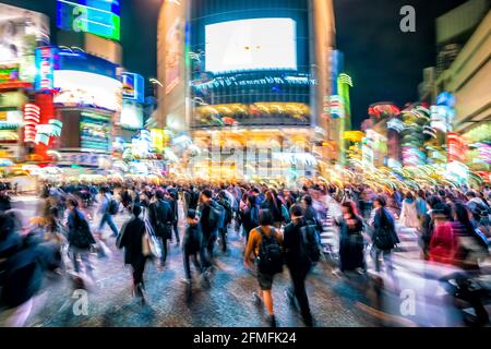 Night shot of pedestrians crossing road full of mopeds in busy