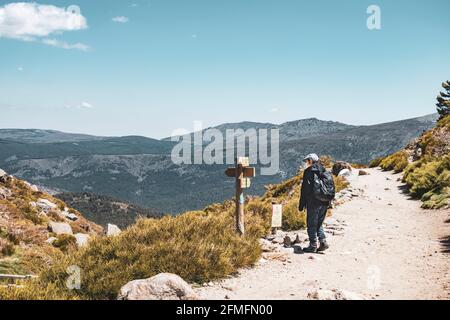 Hiker in the mountain with backpack and mask reading directions. Horizontal photo. Stock Photo
