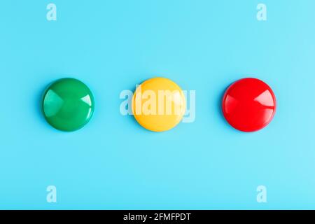 Green yellow and red round magnet in a row on a blue background in the form of a traffic light symbol. The concept of evaluation, satisfaction, status Stock Photo