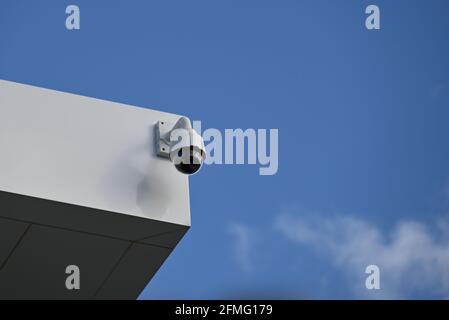 A white dome security camera, part of a CCTV system, attached to a white building Stock Photo