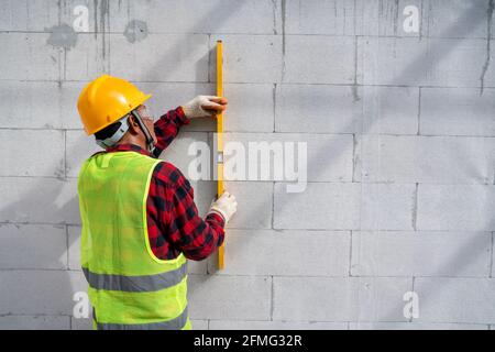bricklayer builder  using the water level, check the inclination of autoclaved aerated concrete blocks. Walling, installing bricks on construction sit Stock Photo
