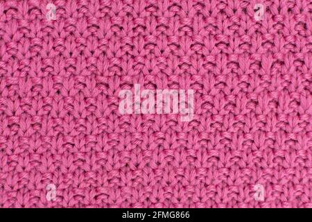 Pink knitted fabric pearl woolen background. The structure of the fabric with a natural texture. Fabric background. Knitted woolen background. Stock Photo