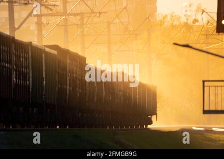 Train cars on railway tracks. Sunlight that penetrates the fog and creates beautiful rays. Motion blur at high speed. Freight transportation. Stock Photo