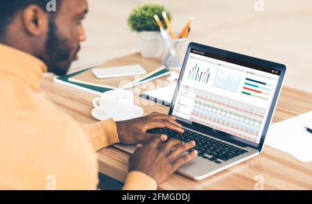 Black guy working on laptop, analysing stocks and markets Stock Photo