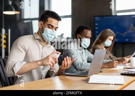 International workers wearing medical masks using sanitizer Stock Photo