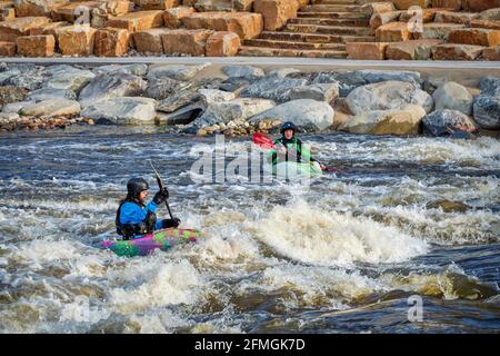 Fort Collins, CO, USA - May 7, 2021: Young male kayakers surfing a wave in the Poudre River Whitewater Park.