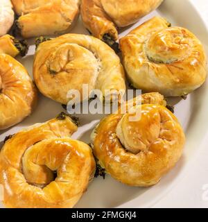 Mediterranean cuisine. Food banner with a national Greek causing with homemade pies with feta cheese and spinach on a white background. Healthy home b Stock Photo