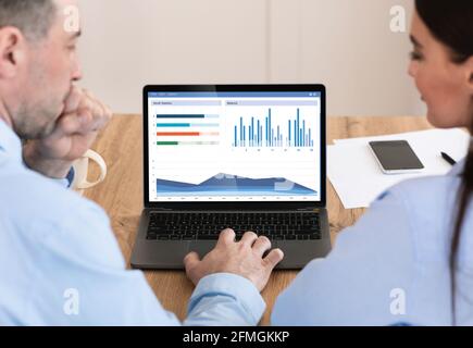 Back view of business team analysing market, using laptop Stock Photo