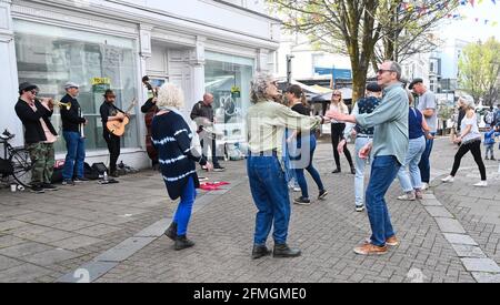 Brighton UK 9th May 2021 - An impromptu dance in the street on a warm sunny afternoon in Brighton's East Street as a jazz band gets visitors back in the swing of things with more lockdown restrictions due to ease further in England next week on 17th May  : Credit Simon Dack / Alamy Live News Stock Photo