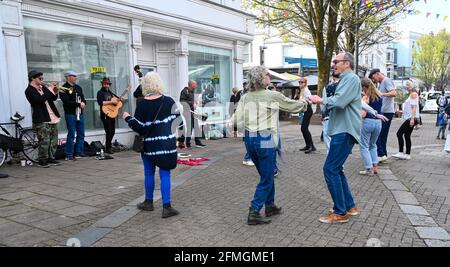 Brighton UK 9th May 2021 - An impromptu dance in the street on a warm sunny afternoon in Brighton's East Street as a jazz band gets visitors back in the swing of things with more lockdown restrictions due to ease further in England next week on 17th May  : Credit Simon Dack / Alamy Live News Stock Photo
