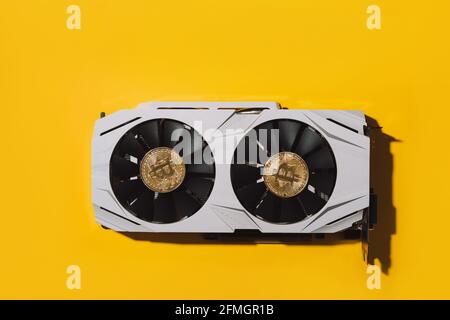 There are two bitcoins on the video card on yellow background. Cryptocurrency mining concept Stock Photo