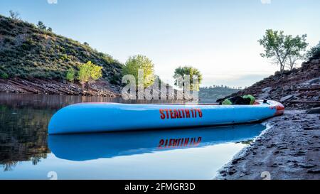 Fort Collins, CO, USA - July 30, 2020: Long and narrow racing stand up paddleboard (Stealth by Mistral SUP) on a calm mountain lake in early summer - Stock Photo