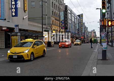 Taxi cabs and a skate boarder make their way down Granville Street at dusk in Vancouver, British Columbia, Canada Stock Photo