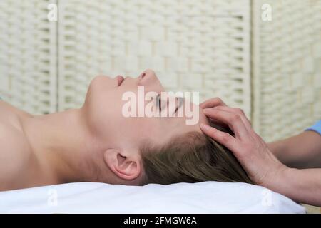 beautiful young woman getting facial massage in the beauty salon, close-up portrait, side view Stock Photo