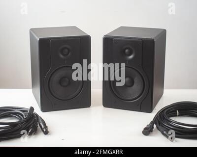 Black Pro Studio Speakers with Cables against a White and Gray Surface Stock Photo