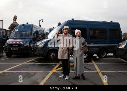 A couple in front of a police barricade looks on as protesters (not pictured) make their way towards Place de la Concorde near the Champs-Elysees Aven Stock Photo