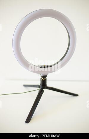 Ring lamp on tripod on white table. Stock Photo