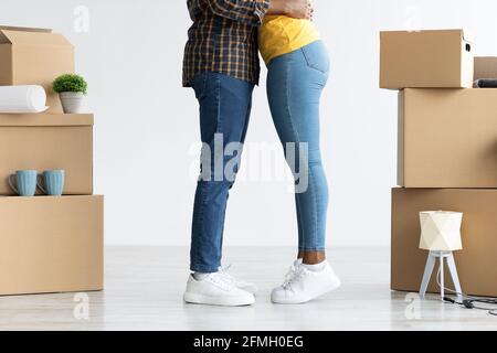 Cropped image of black couple embracing among cardboard boxes after relocation Stock Photo