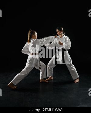 Two female karatekas in white kimono, strike in action, dark background.  Karate fighters on workout, martial arts, women fighting competition Stock  Photo - Alamy