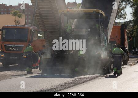 Madrid, Spain - May 5, 2021: Maintenance, rehabilitation and paving of streets in the downtown area of Madrid, Retiro district, using asphalt finisher Stock Photo