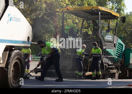 Madrid, Spain - May 5, 2021: Maintenance, rehabilitation and paving of streets in the downtown area of Madrid, Retiro district, using asphalt finisher Stock Photo