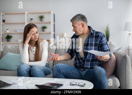 Mature couple having heated discussion about family budget, in trouble paying all bills, checking financial documents Stock Photo