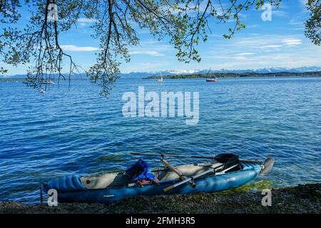 A paddle boat parked on the shore of a lake. In the background snow covered mountains. Stock Photo