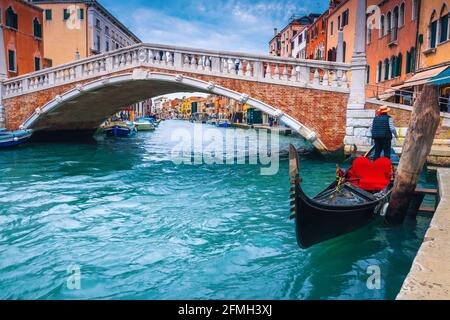 Stunning street view in Venice with amazing water canal and waterfront buildings. Anchored gondola with venetian gondolier on the water canal, Venice,