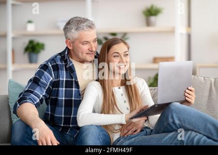Happy mature couple using laptop, relaxing together at home Stock Photo