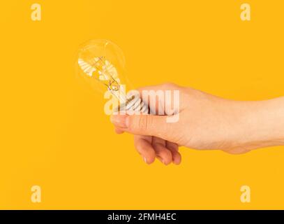 Woman hand with led light bulb, led lamp on orange yellow isolated background Stock Photo